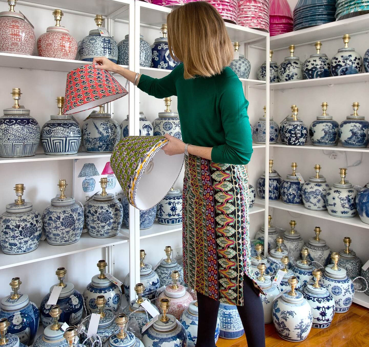 A woman in a room filled with  blue-and-white ceramic ginger jar lamps